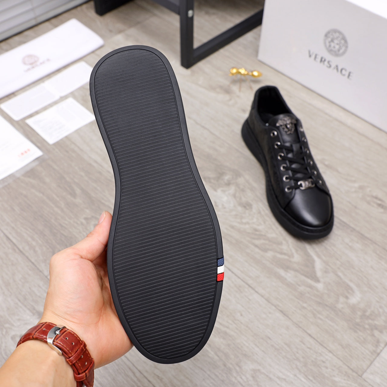 Black Versace sneaker outsole with textured tread and red stripe detail on side