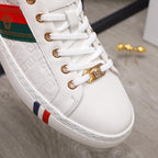 Close-up of white sneakers: gold lace eyelets, multicolor stripe panel, textured side