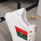 White sneaker side view with embossed pattern, multicolor stripe panel and gold hardware