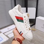 White lace-up sneakers with gold emblem detail and multicolor strap band on side