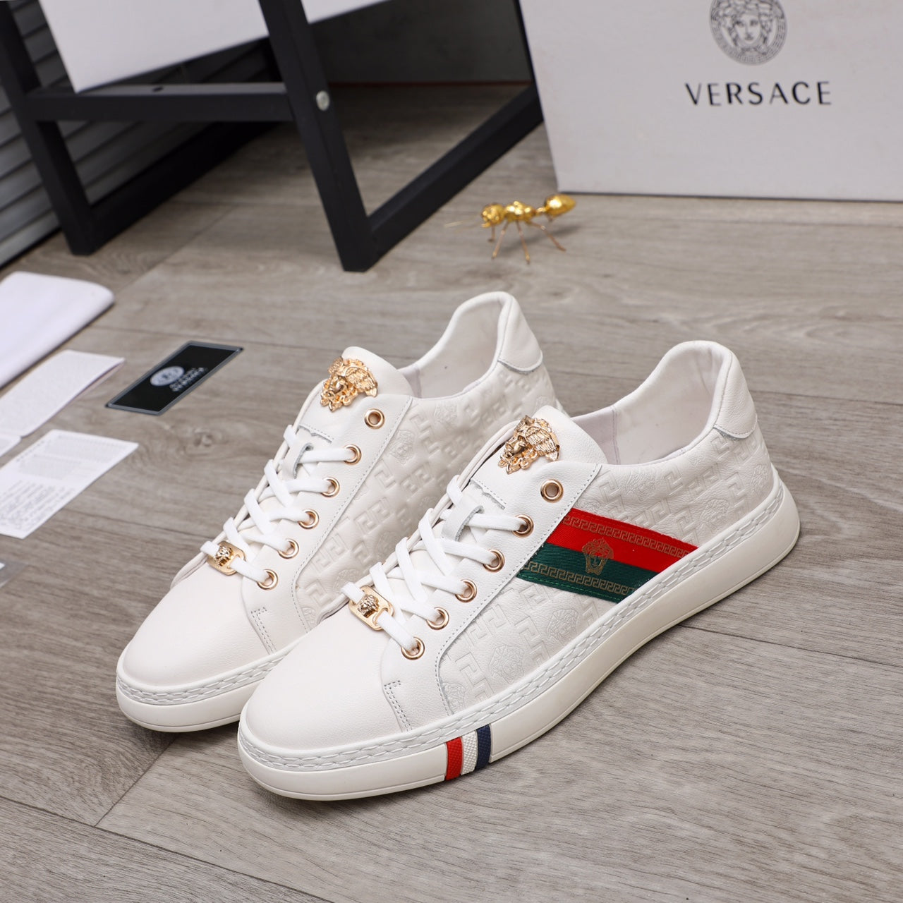 White Versace sneakers with gold-tone eyelets, multicolor stripe detail, lace-up front