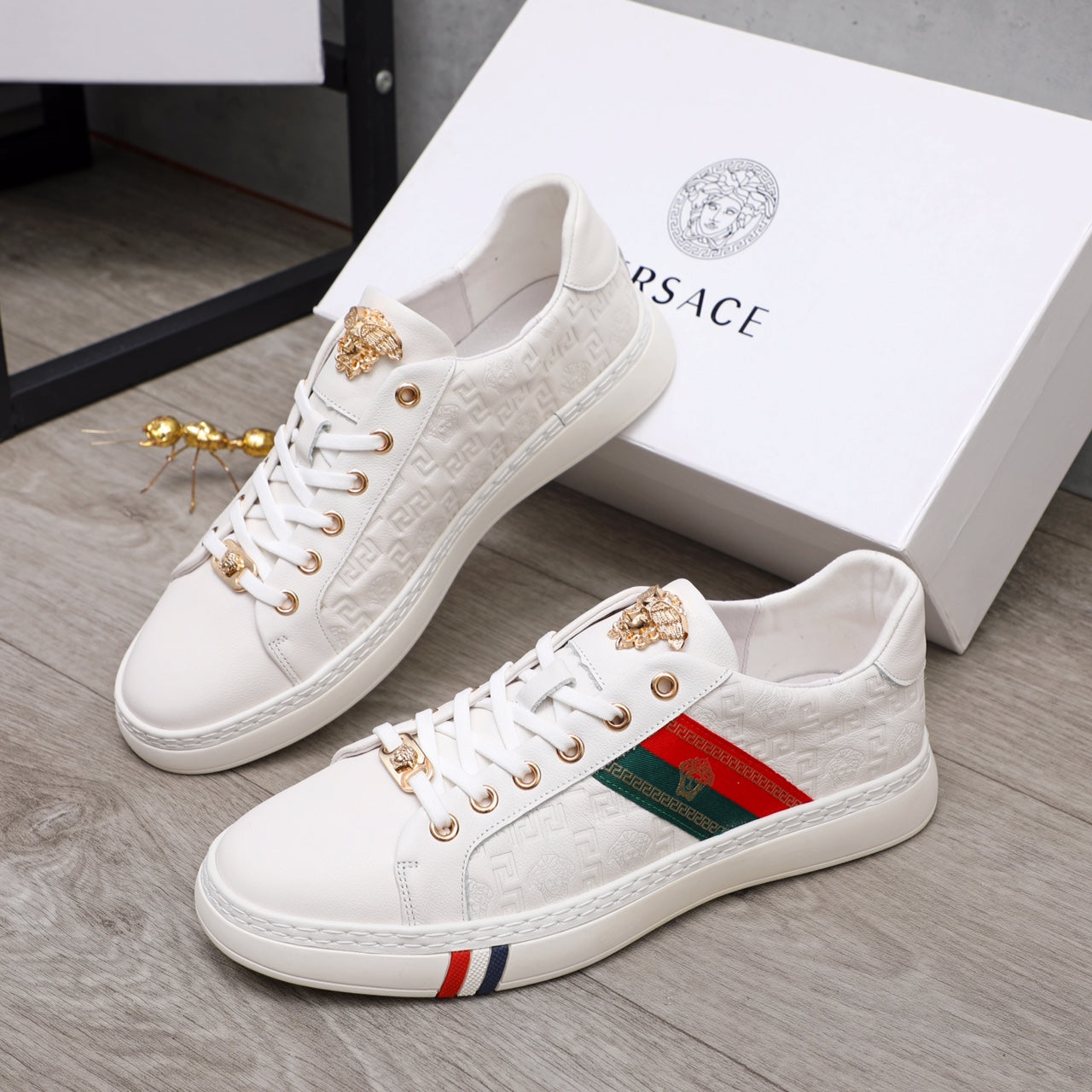 Pair of white Versace sneakers with gold-tone hardware, multicolor stripe and lace-up