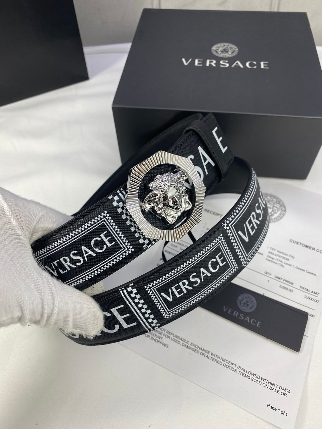 Versace belt close-up in black with logo strap and silver-toned medallion buckle