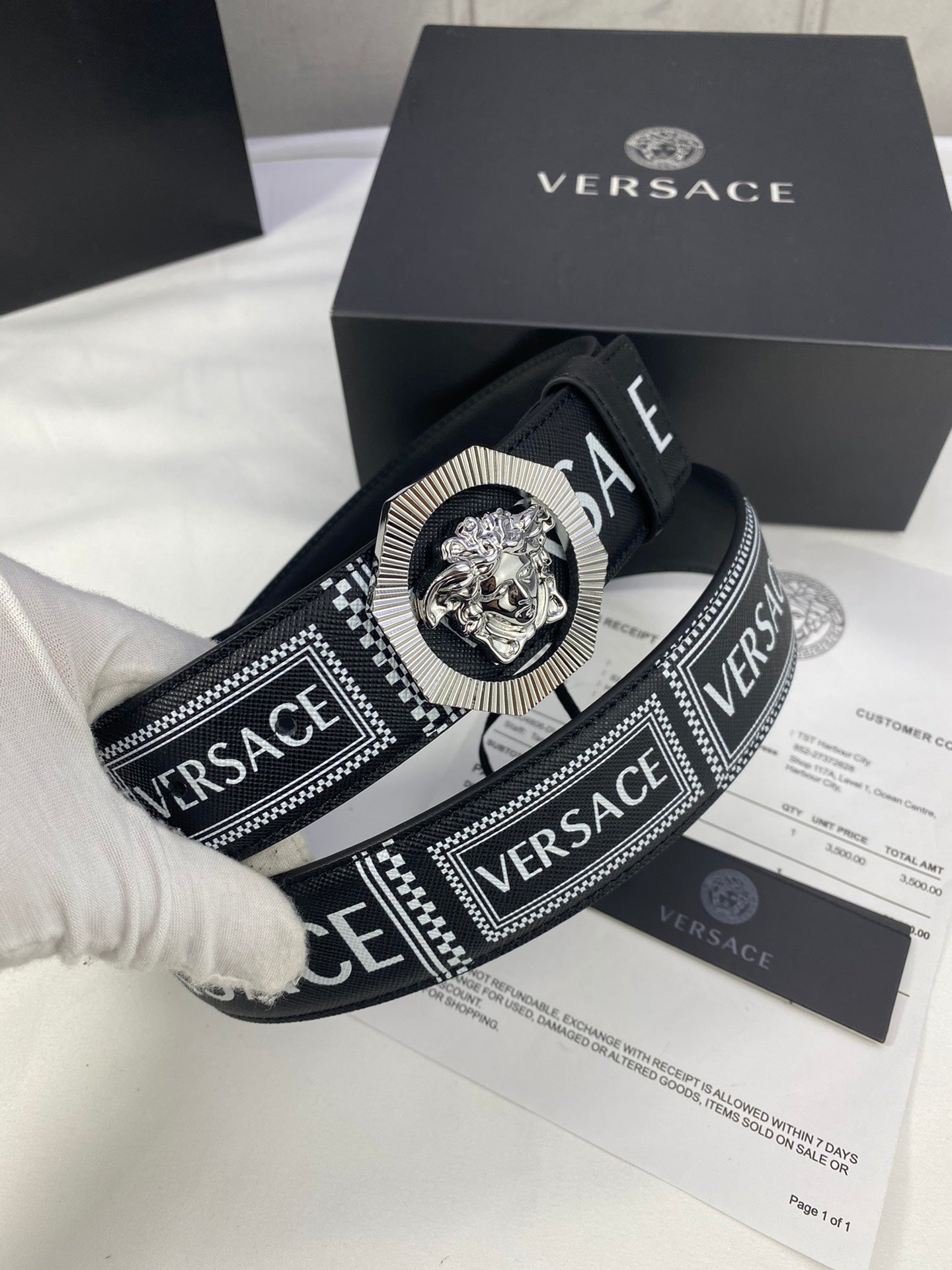 Versace belt close-up in black with logo strap and silver-toned medallion buckle