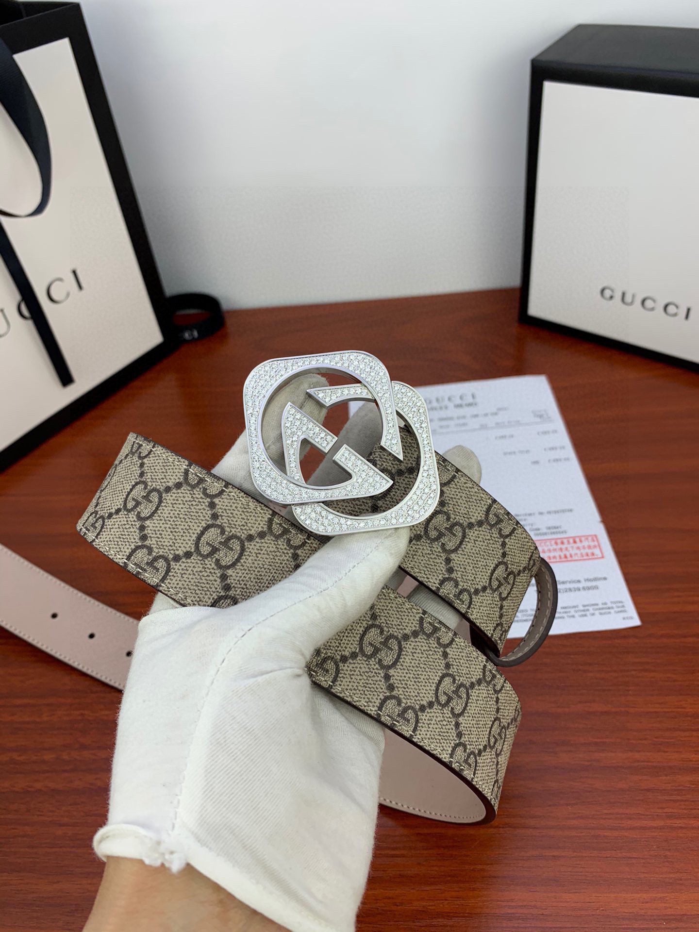 Gucci belt held in hand: beige GG canvas with silver-tone double G buckle