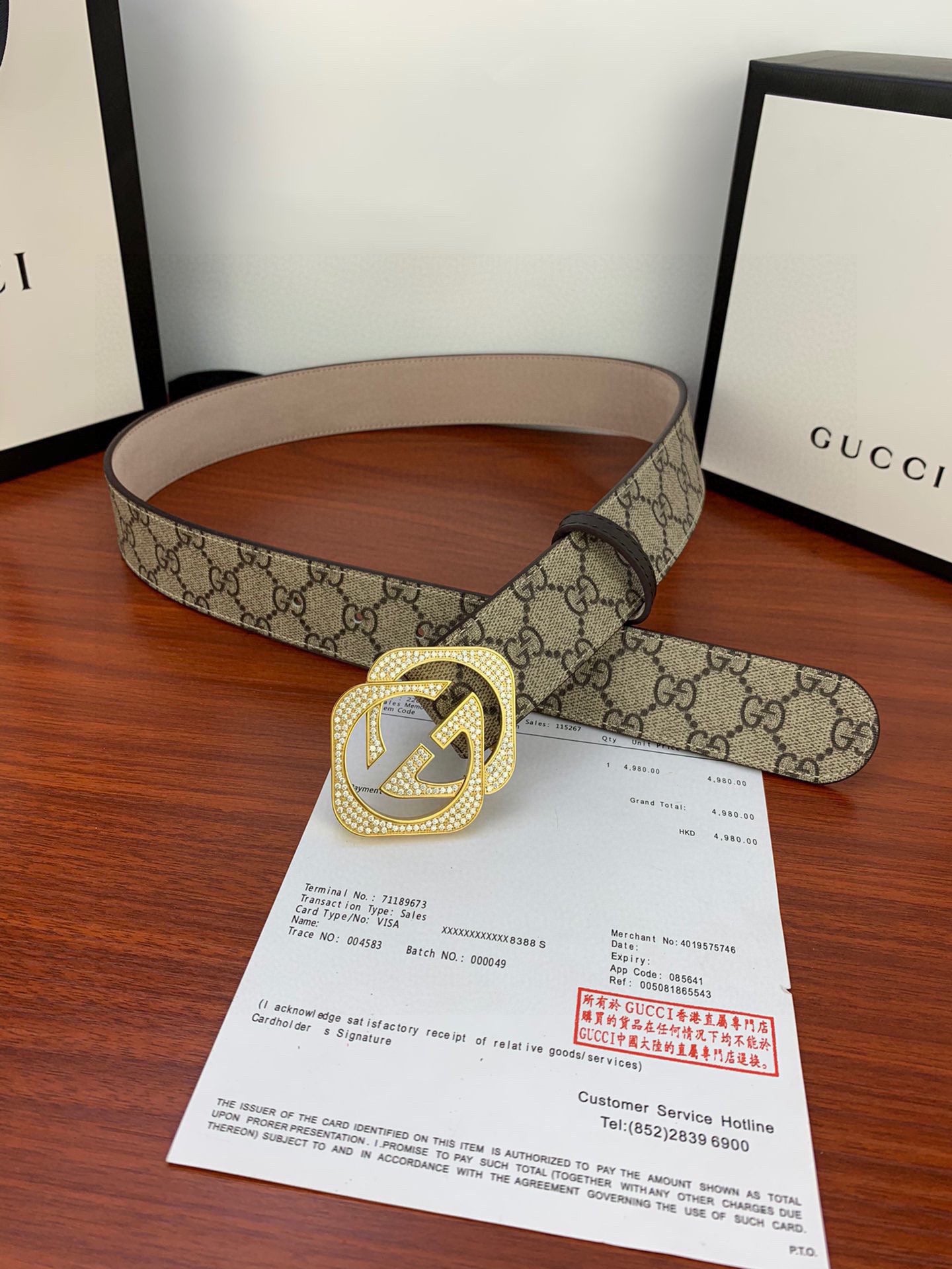 Gucci belt with beige GG canvas and gold-tone double G buckle, rolled on table