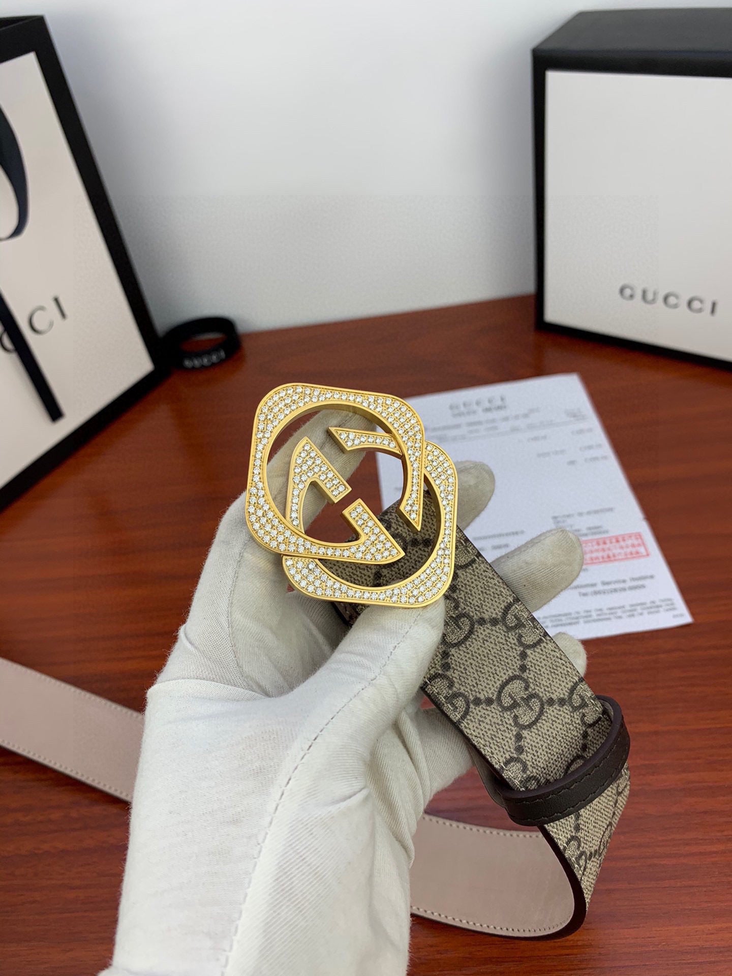 Gucci belt held in hand: beige GG canvas with gold-tone double G buckle