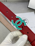 Red leather belt close-up: teal CC-logo buckle and two pin holes