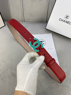 Red leather belt with teal CC-logo buckle, held in gloved hand