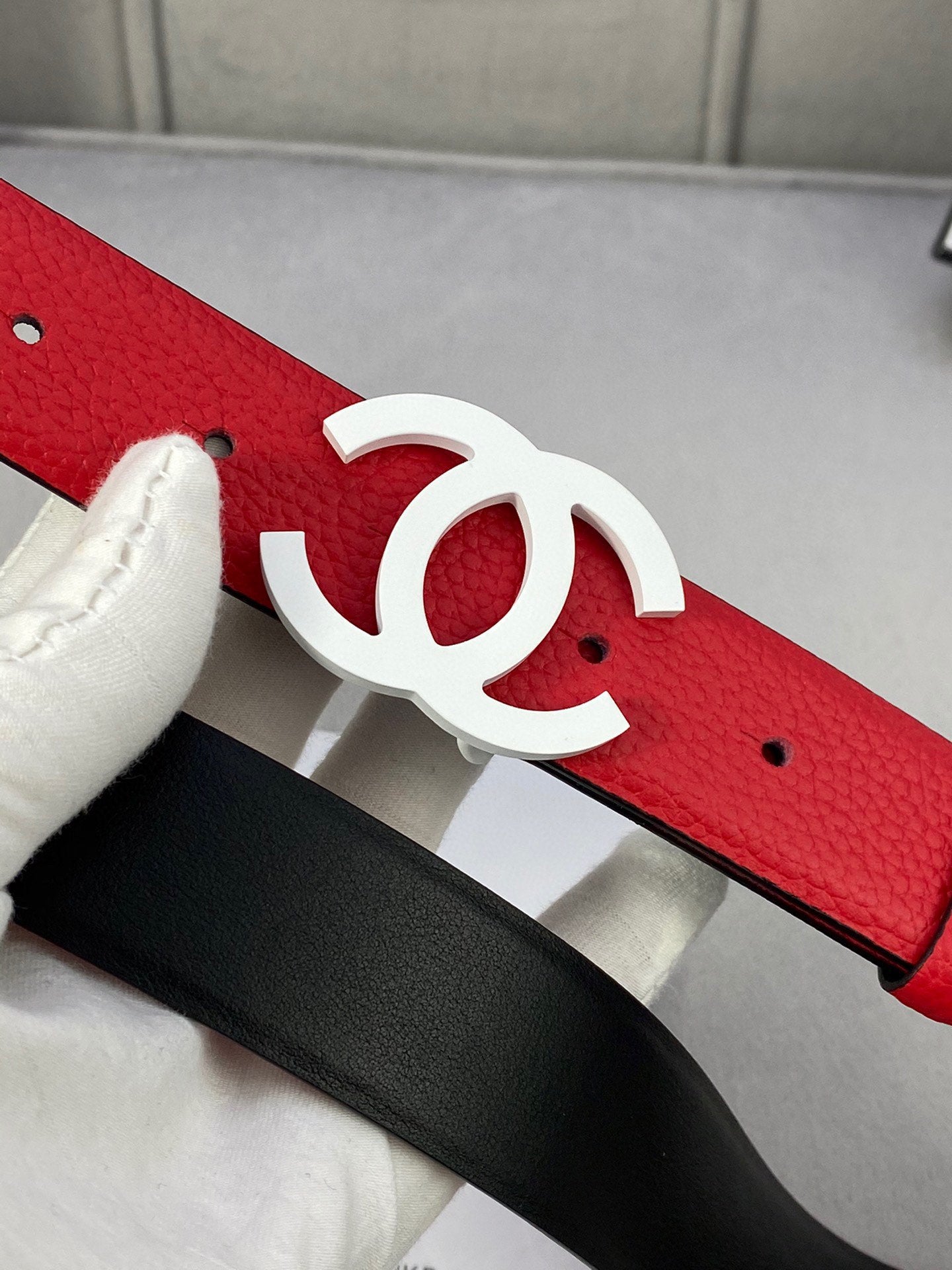 Red leather belt with white CC buckle over black backing strap