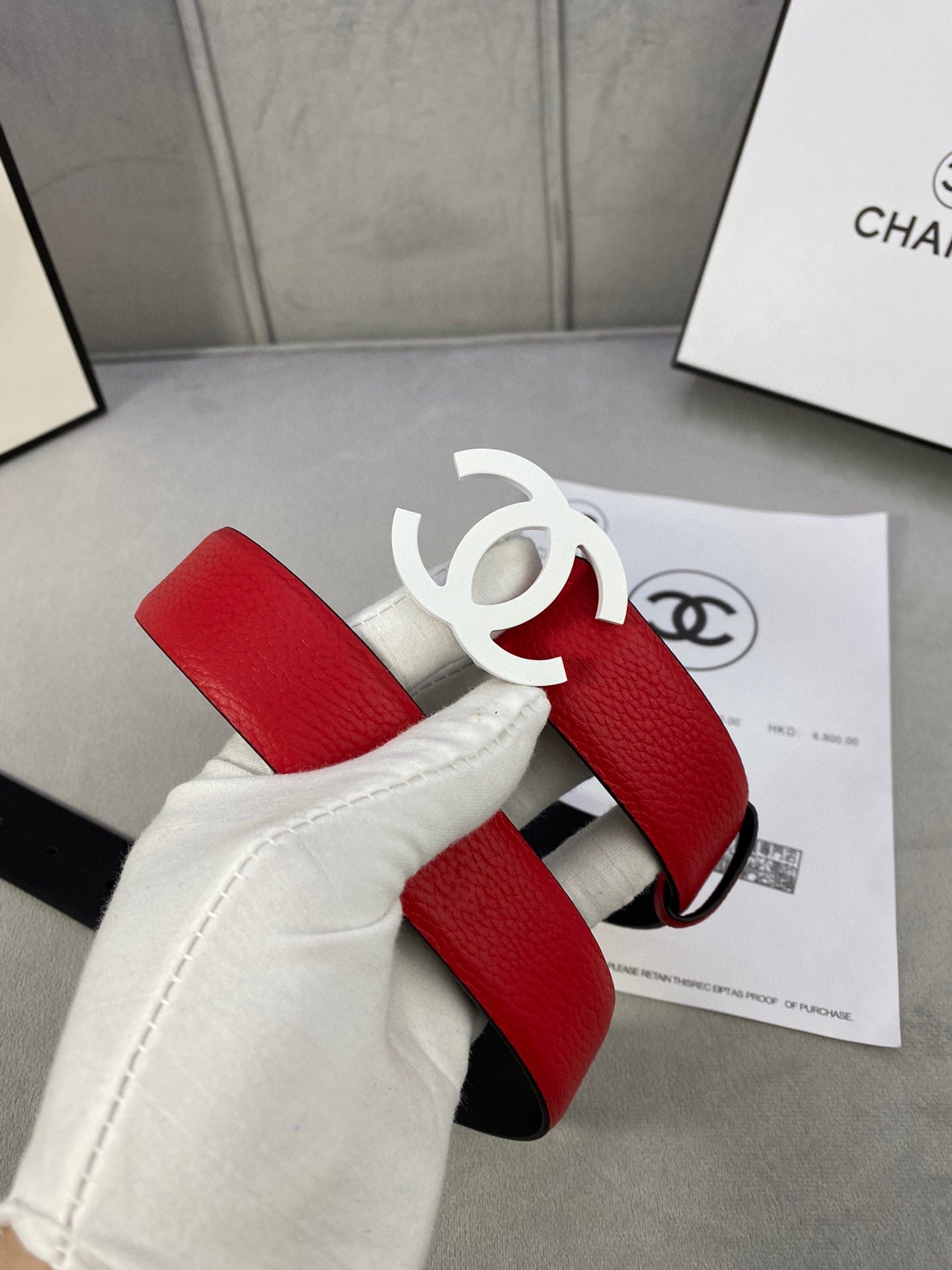 Red leather Chanel belt with white CC buckle and black underside