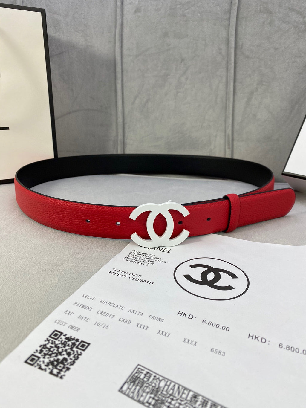 Red leather belt with white CC buckle, black edge visible