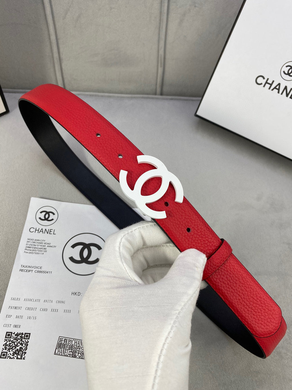 Red leather Chanel belt with white CC logo buckle, visible holes