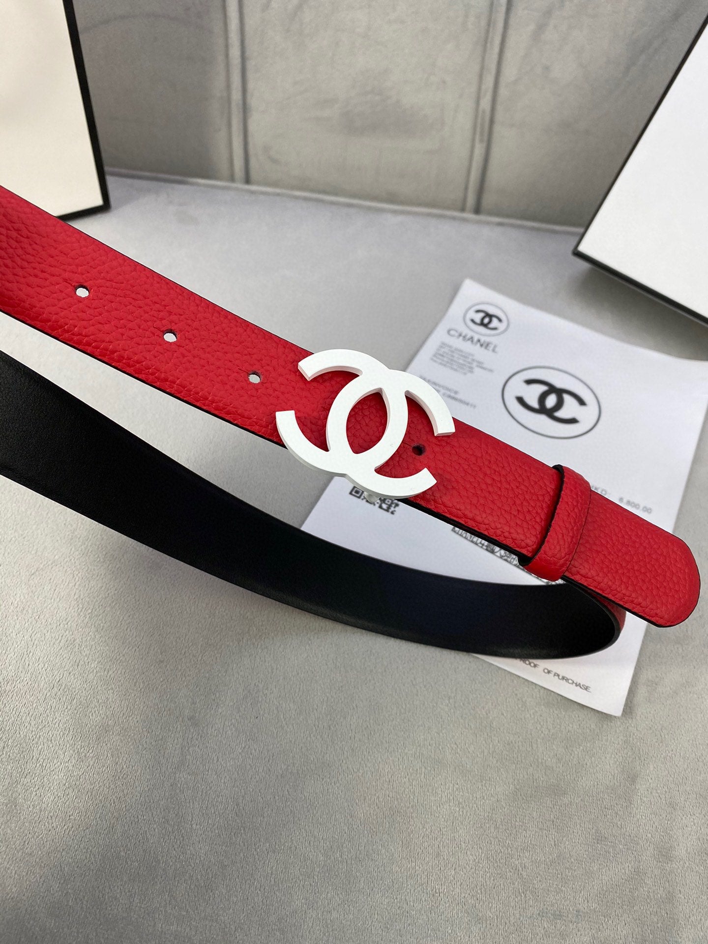 Red leather belt with white CC buckle, black backing strap visible