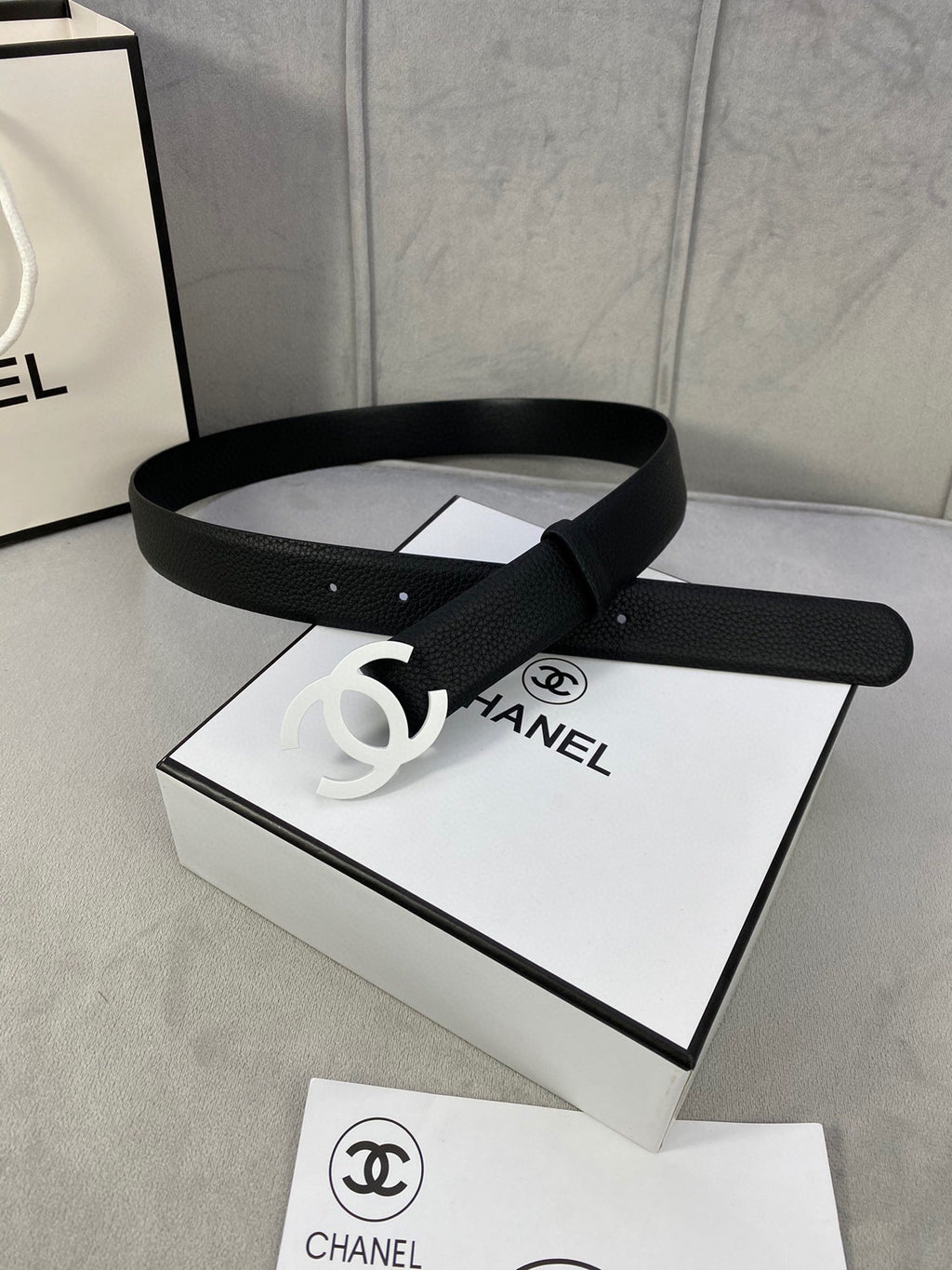 Chanel belt, black leather-look strap with silver CC buckle on a flat display surface.