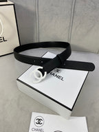 Chanel belt, black leather-look strap with silver CC buckle on a flat display surface.