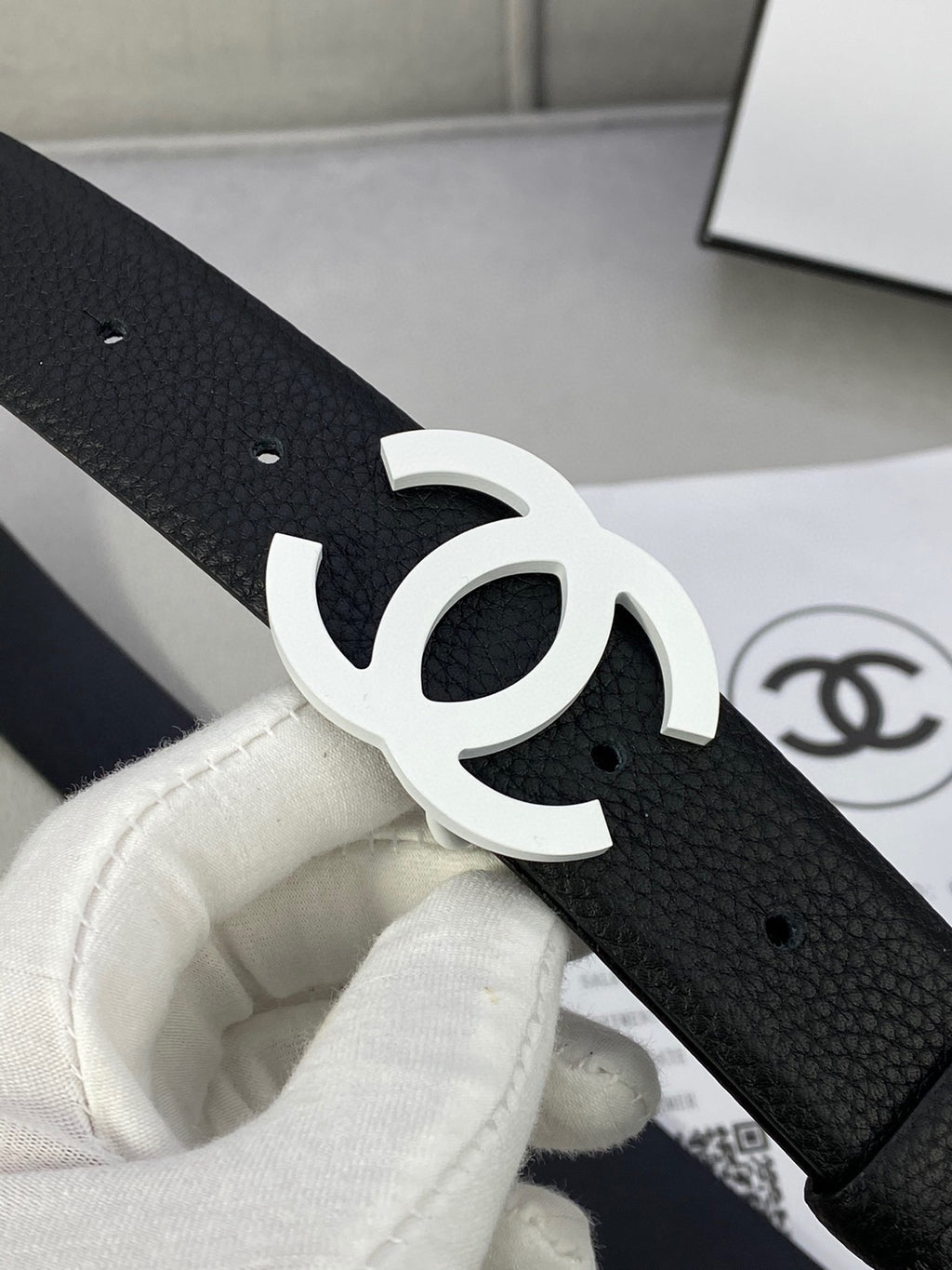 Chanel belt close-up, black textured strap with silver CC buckle and punched holes.