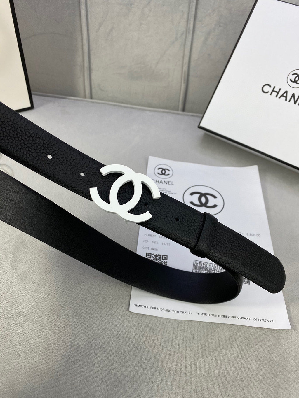 Chanel belt, black leather-look strap with silver CC buckle and hole-punched end.