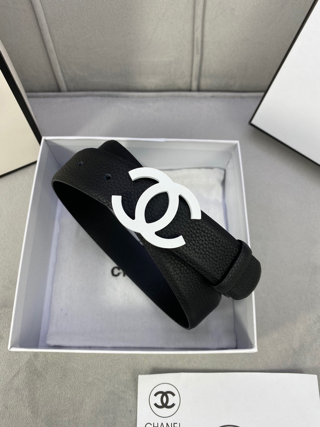Chanel belt, black leather-look strap with silver CC buckle inside a gift box.