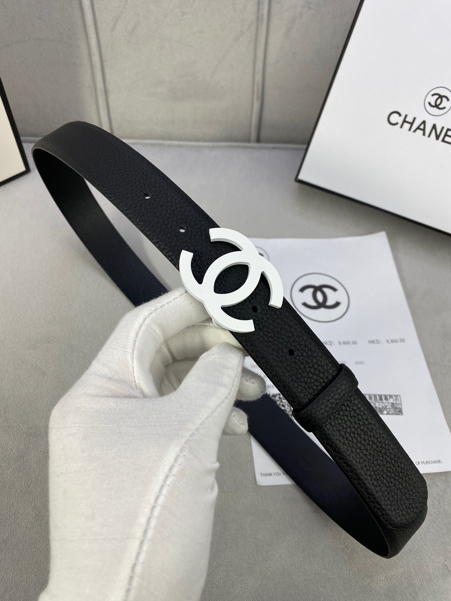Chanel belt, black leather-look strap with silver CC buckle and punched holes.