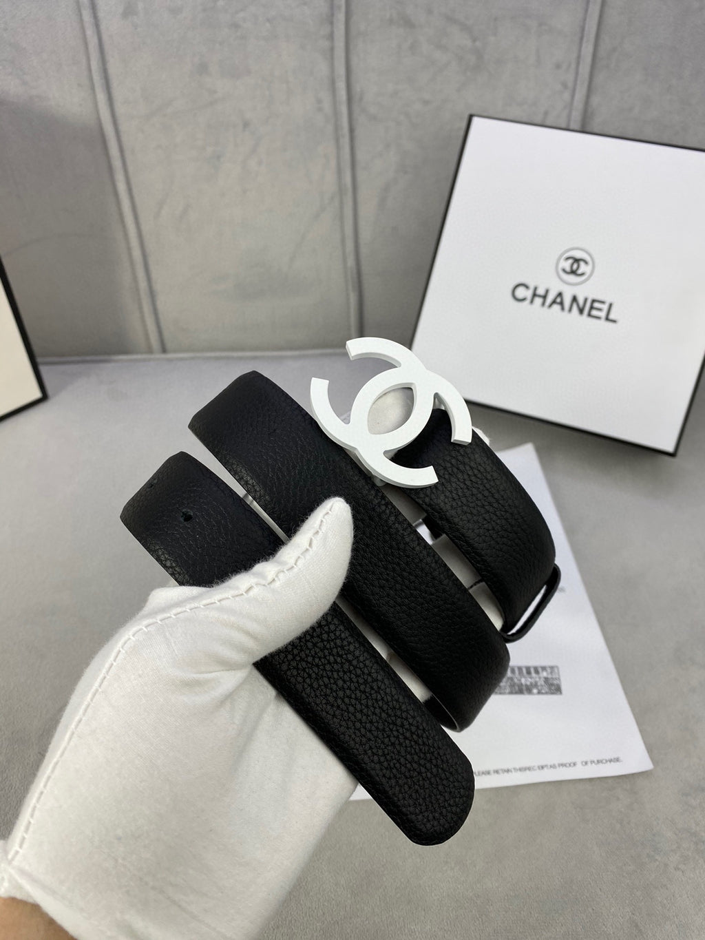 Chanel belt, black textured strap with silver CC buckle and looped strap end.