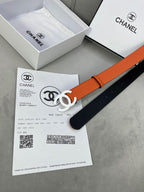 Chanel belt with orange strap, black lining, and white CC buckle next to paperwork