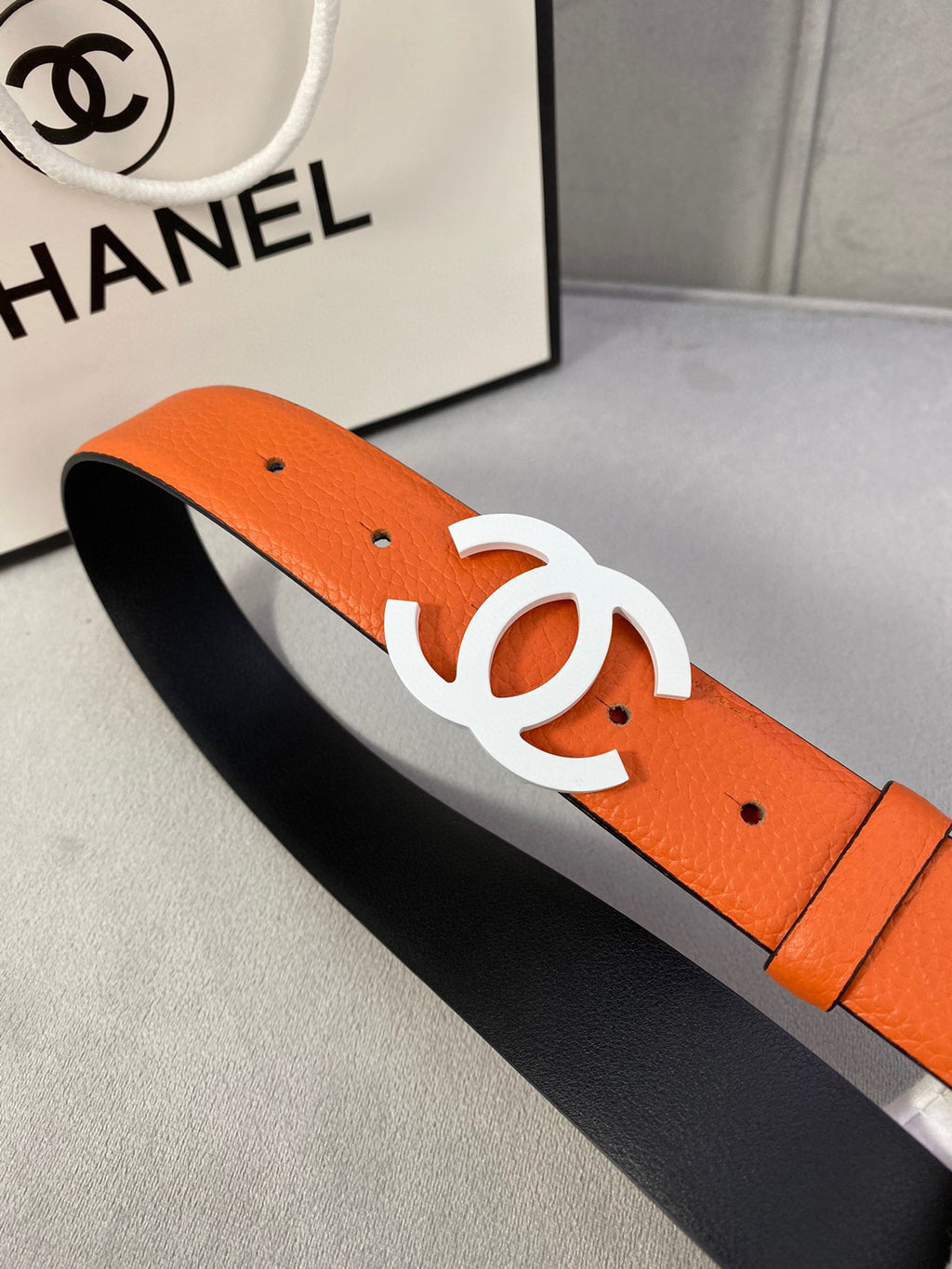 Chanel leather belt with orange strap and white CC buckle on black lining