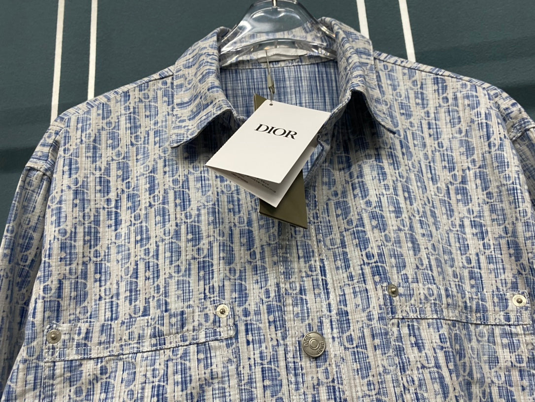 Blue and white patterned button-up shirt with collar and DIOR tag on hanger