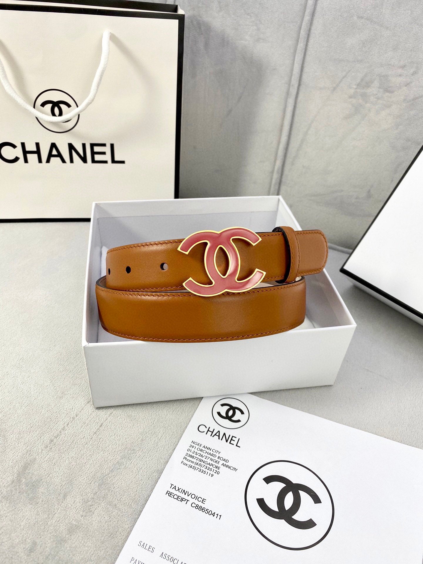 Brown Chanel belt in white box with red CC buckle and perforated strap