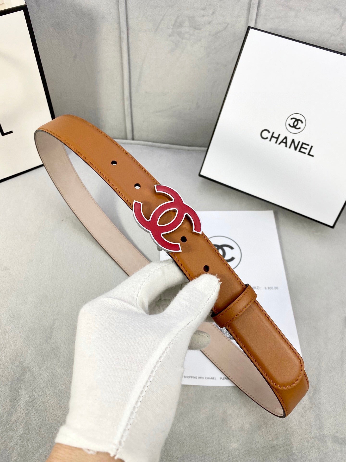 Brown Chanel belt with red CC buckle, shown with strap and holes