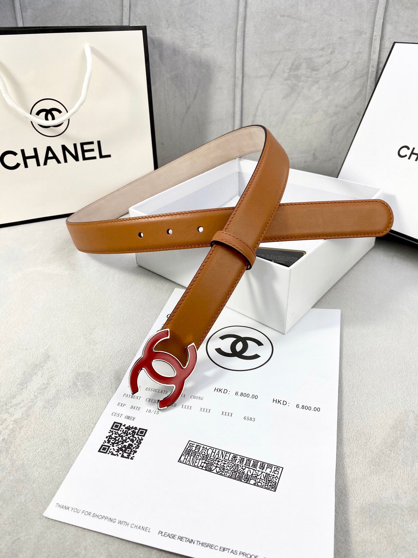 Brown Chanel belt with red CC buckle and adjustable perforated strap