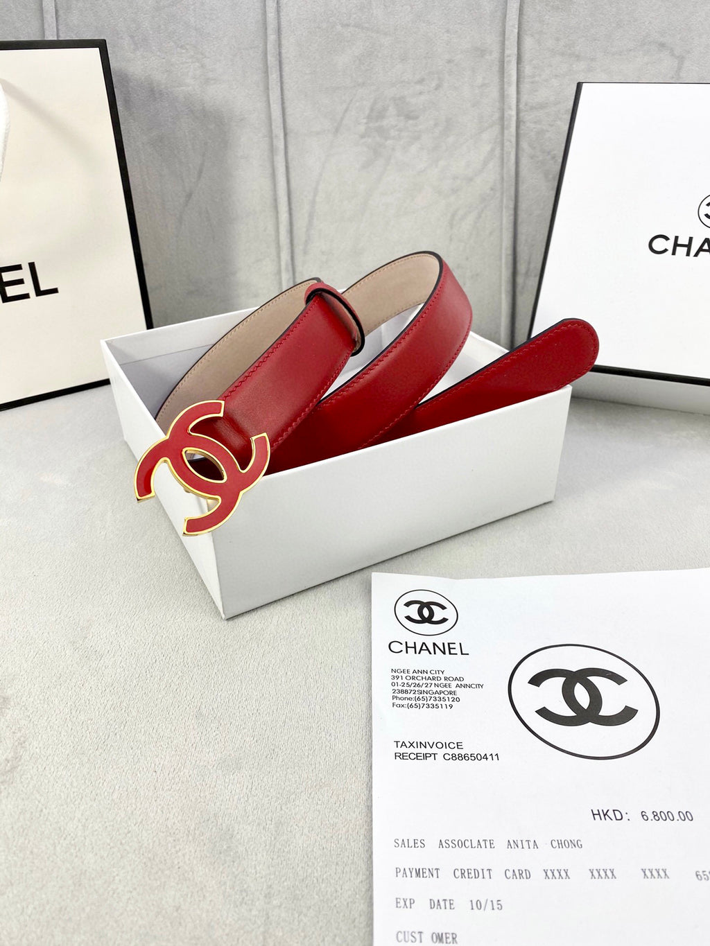 Red leather belt with Chanel CC logo buckle in open box with documents