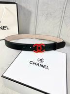 Chanel belt in dark leather with red-and-black CC logo at center, flat strap.