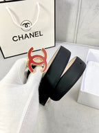 Chanel belt with dark leather strap and red-and-black CC emblem, shown in box.