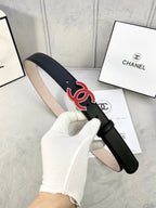 Chanel belt with dark leather strap and red-and-black CC logo, held up for view.