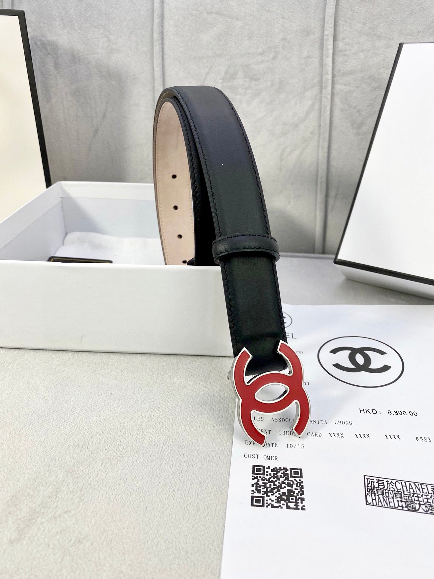 Chanel belt with dark leather strap, visible beige underside and red-and-black CC logo.