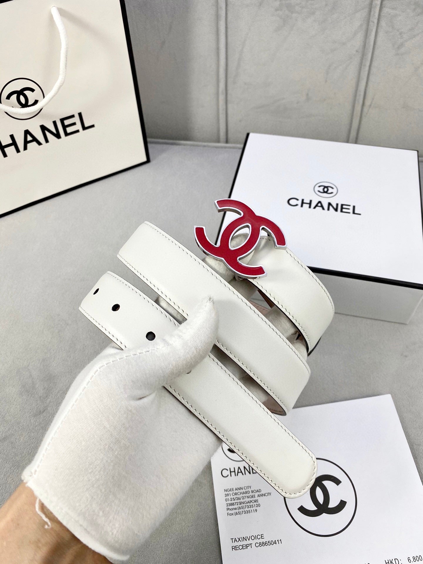 White Chanel belt with red logo buckle and stitched leather strap
