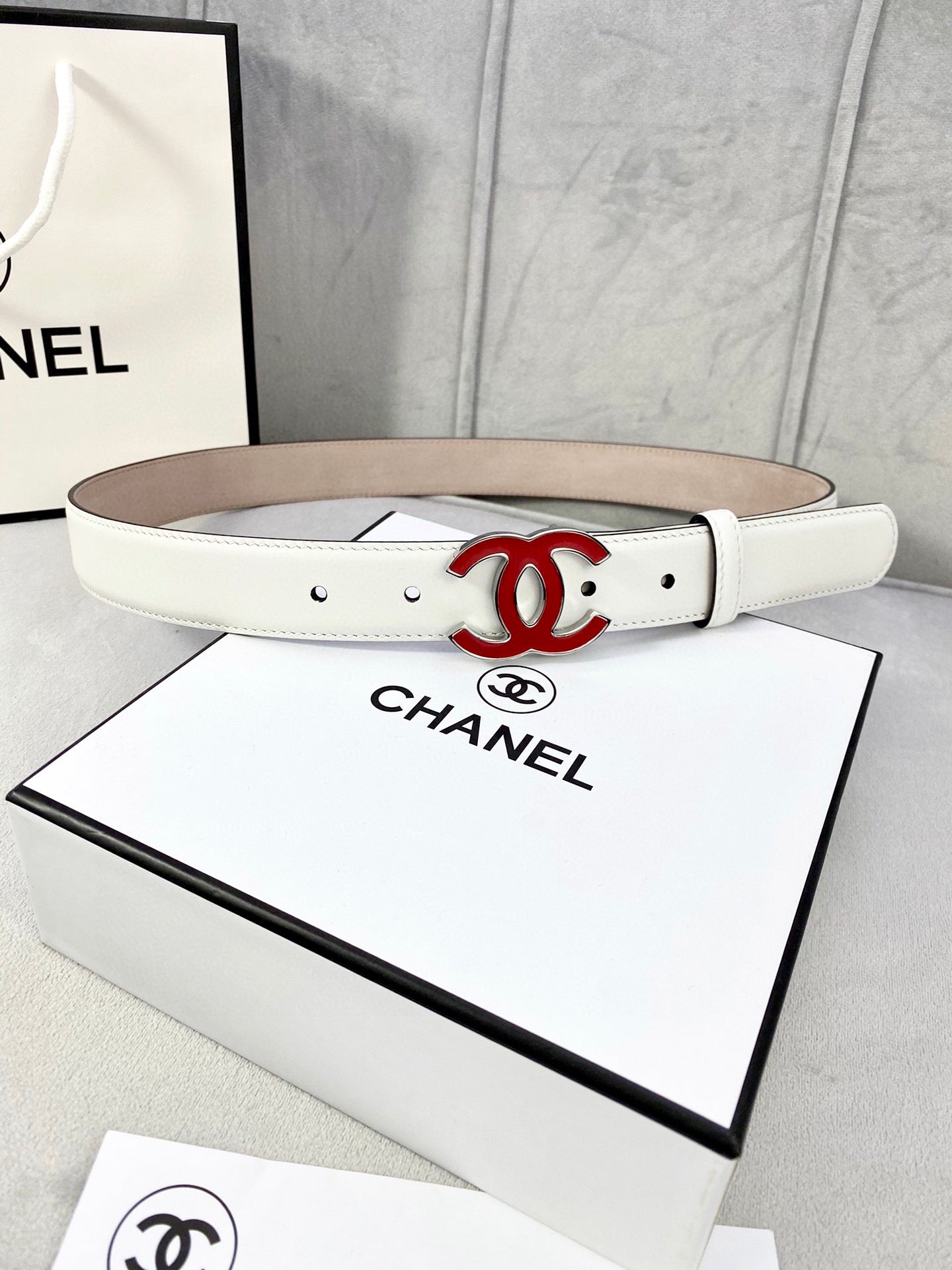 White Chanel belt with red logo buckle and adjustable holes