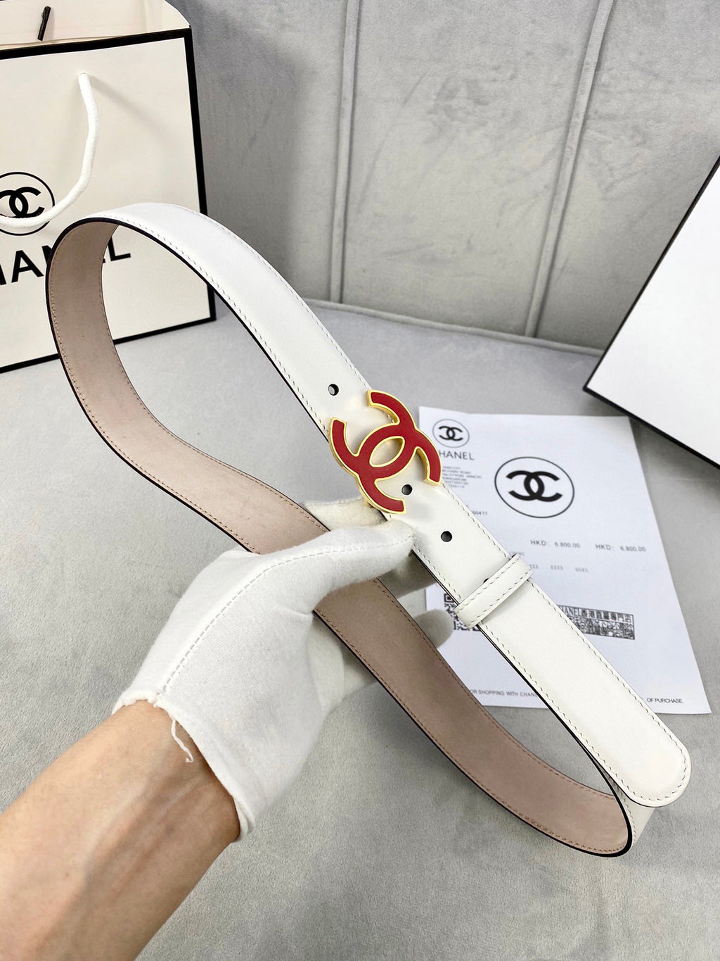 White Chanel belt with red logo buckle, side view of leather strap