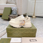 Gucci unisex sneakers on box, white leather look with logo graphic on side