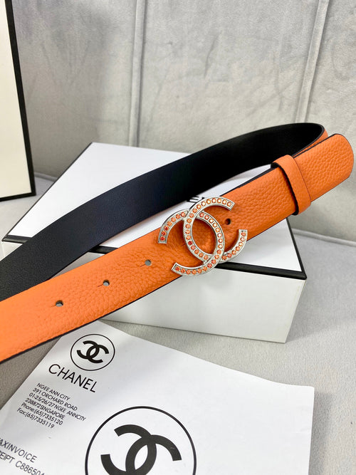 Orange leather belt with gold jeweled buckle and black underside, adjustable strap