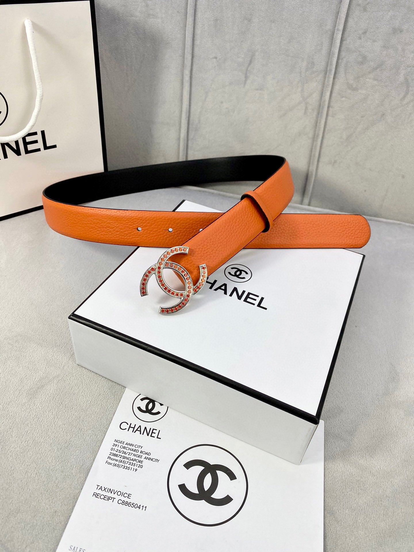 Orange leather belt with gold jeweled CC buckle, two-piece look and black underside