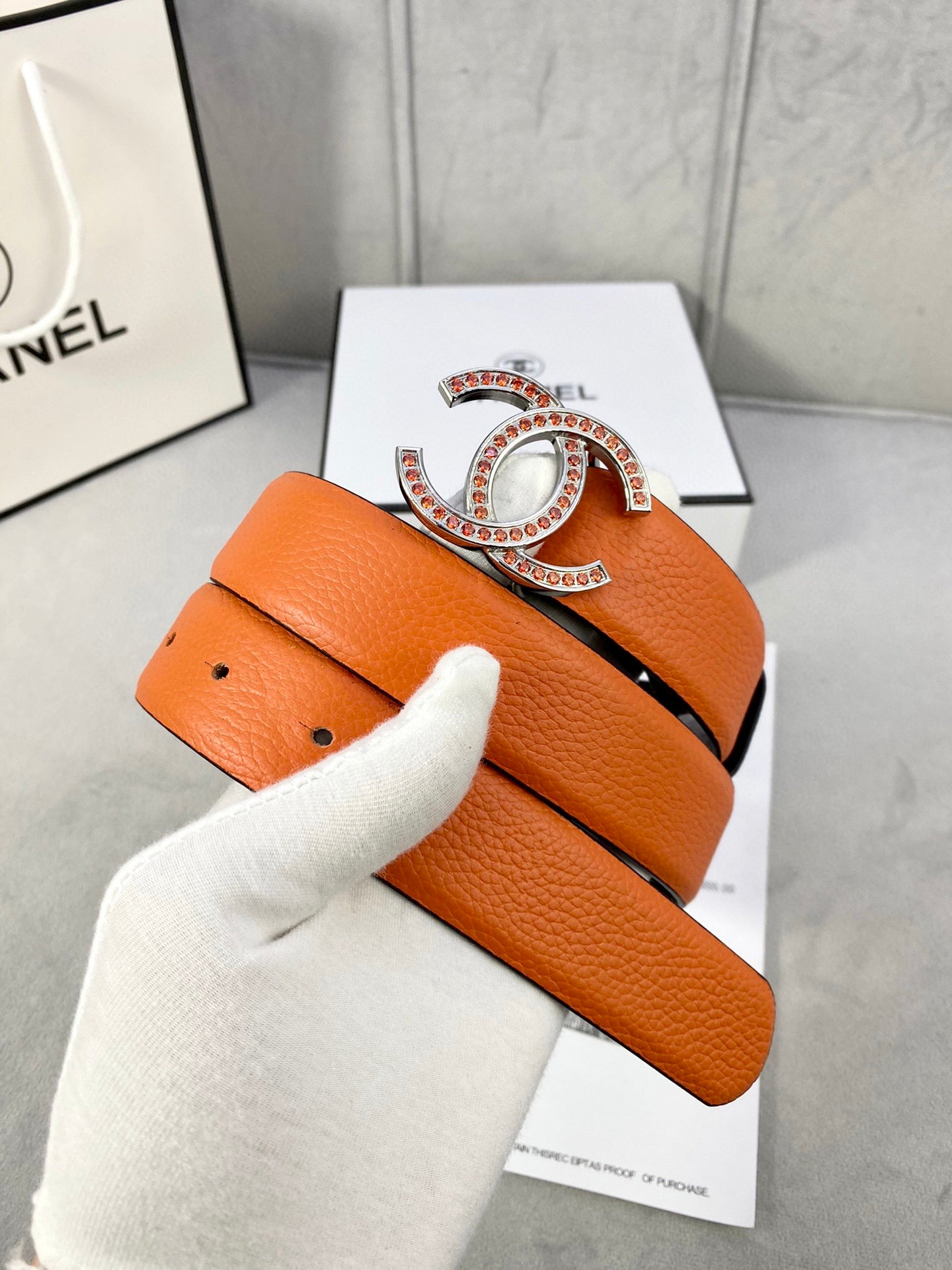 Orange leather belt with gold jeweled CC buckle and folded strap end