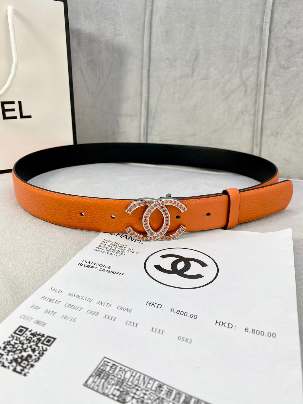 Orange leather belt with gold jeweled CC buckle, punched holes and black lining