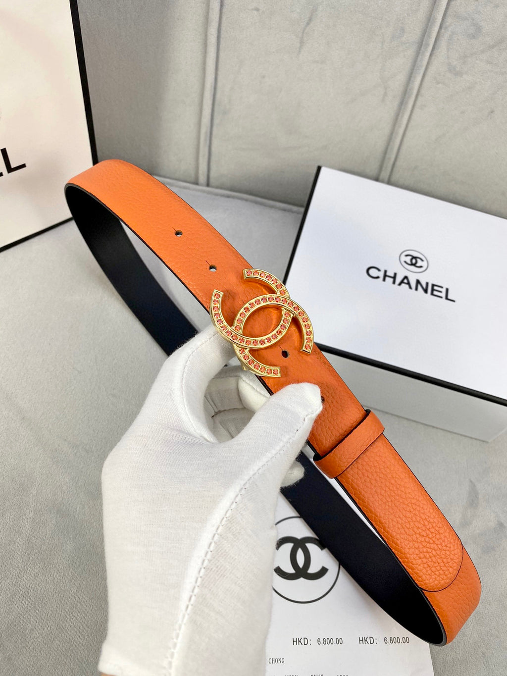 Orange leather belt with gold jeweled buckle and black-lined reverse strap