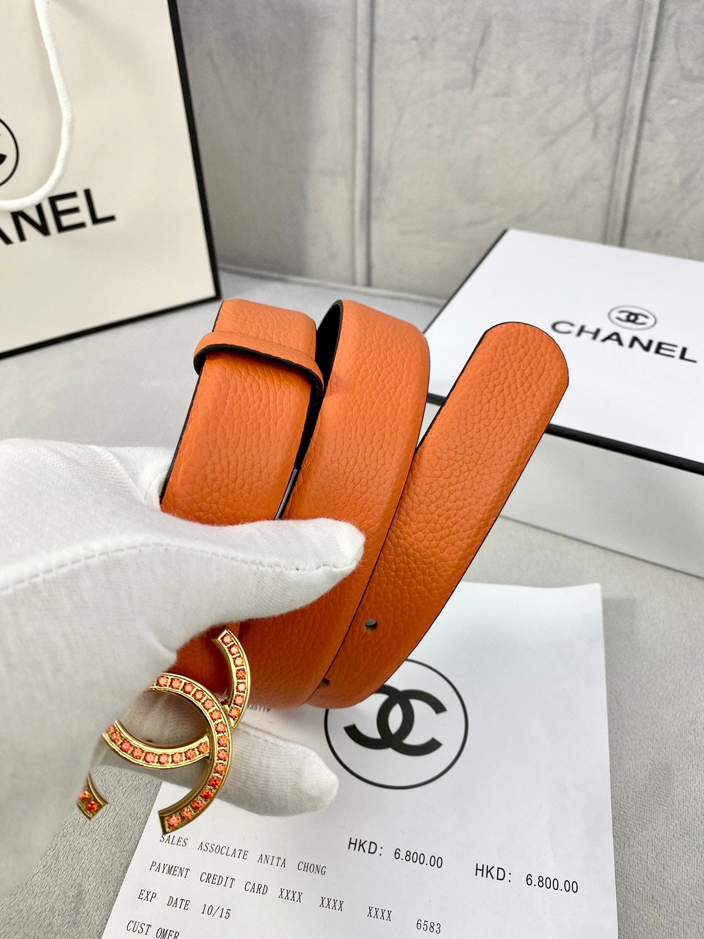Orange leather belt with gold jeweled CC buckle and multiple punched holes