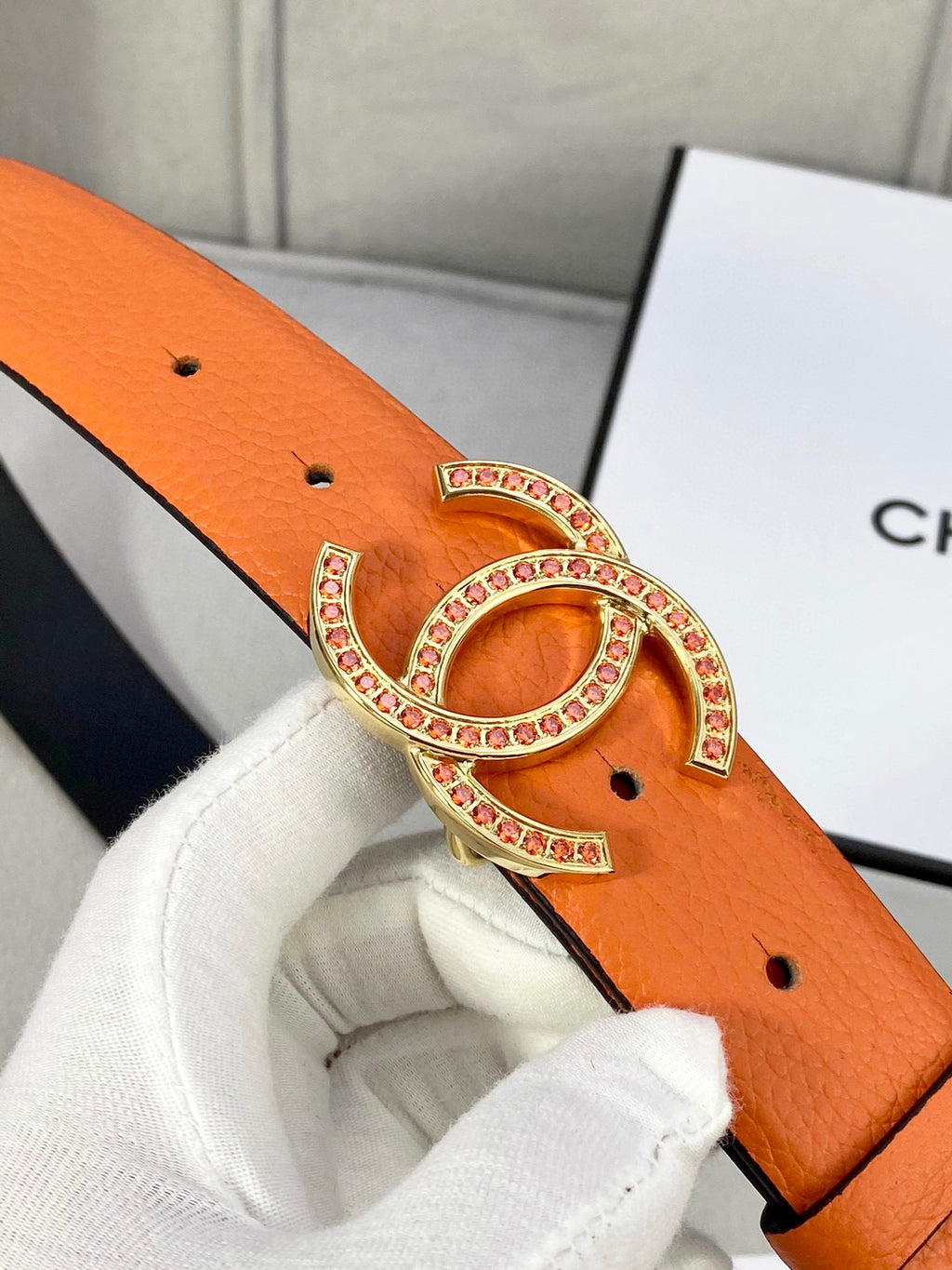 Orange leather belt with gold jeweled CC logo buckle, studded edge and hole
