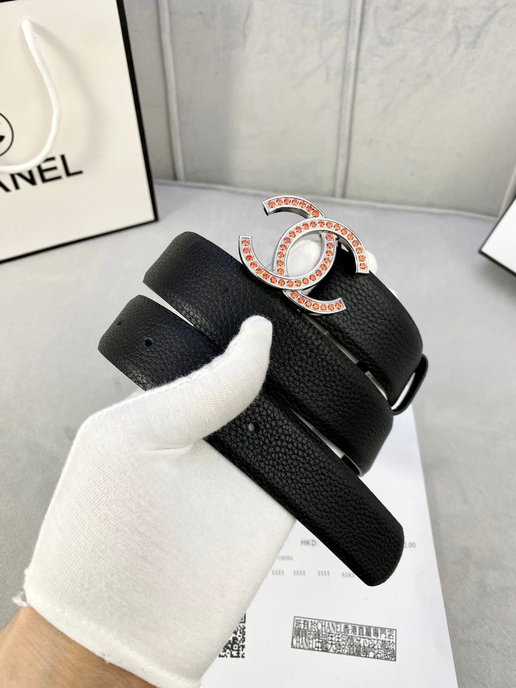 Chanel belt on white glove: black textured strap with gold-tone CC buckle