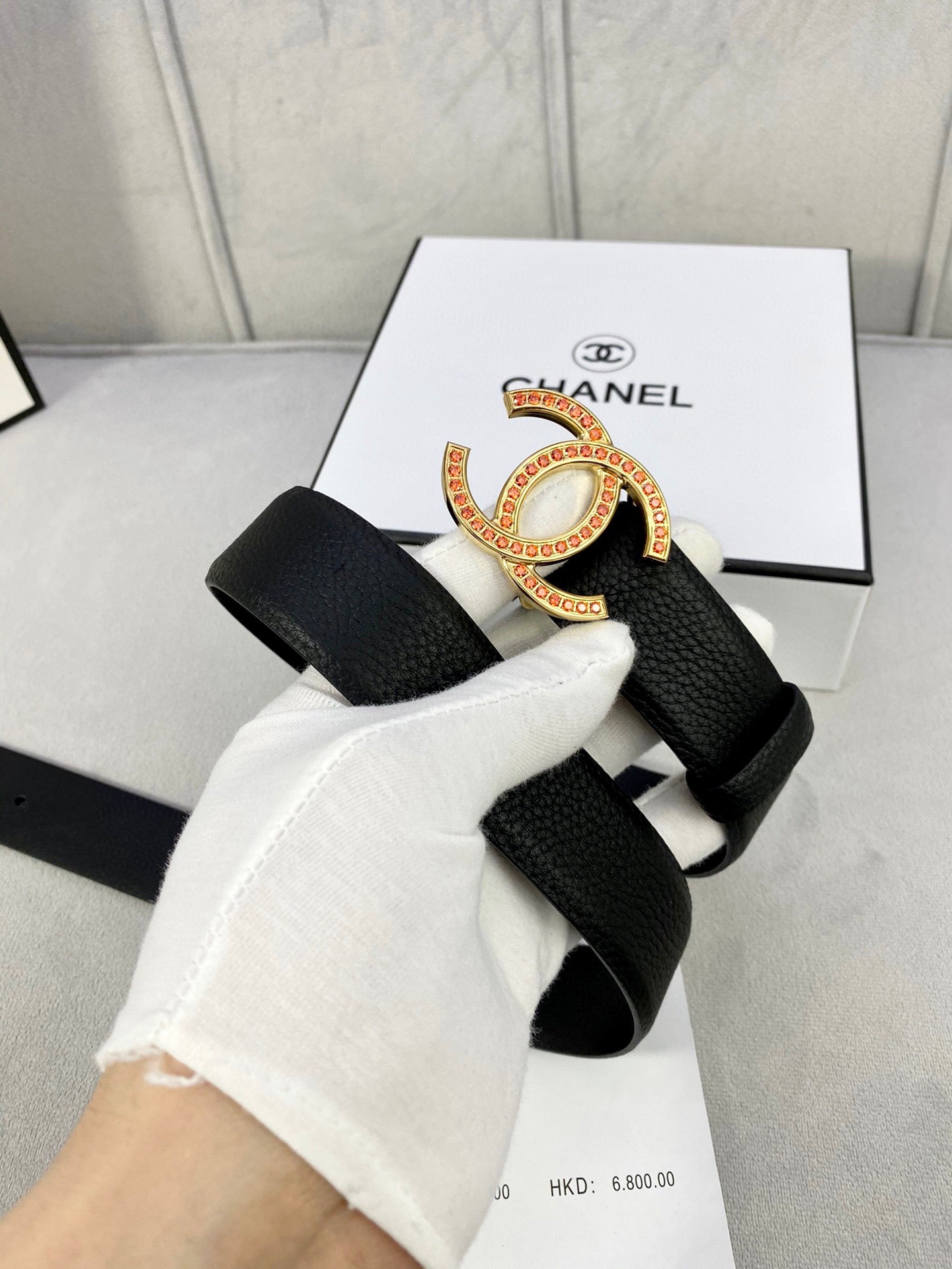 Chanel belt styled on white glove: black strap with gold-tone CC buckle