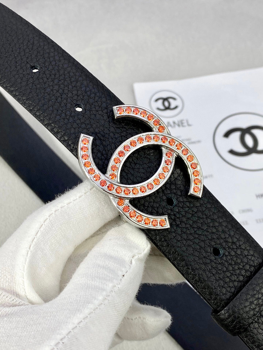 Chanel belt buckle close-up: black strap with gold-tone CC logo and red stones